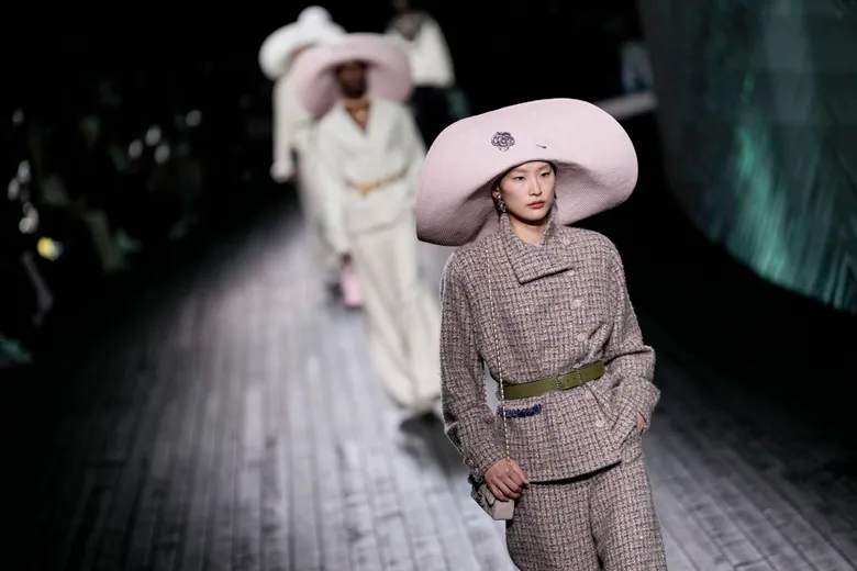 Maximalist hats and structured tailoring take center stage on the runway, turning classic silhouettes into high drama.