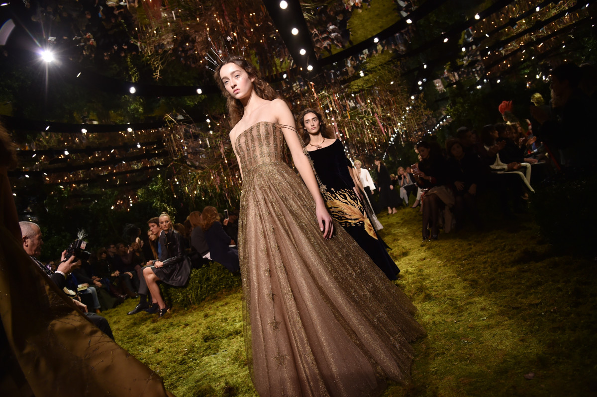 Models walking the runway in stunning gowns, with an ethereal atmosphere, embodying the empowerment of Dior's feminist philosophy.